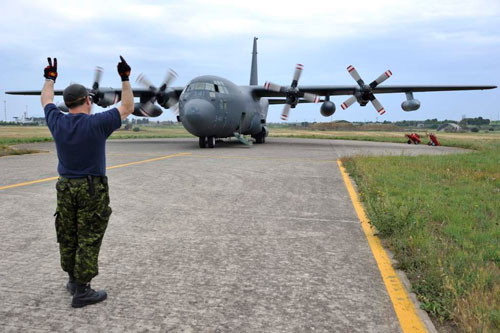 Trapani, Italy — Master-Corporal William Stamper, Task Force Libeccio Avionics Technician, marshals a CC-130 Hercules prior to takeoff during Operation Mobile in Trapani, Italy on May 24, 2011.
