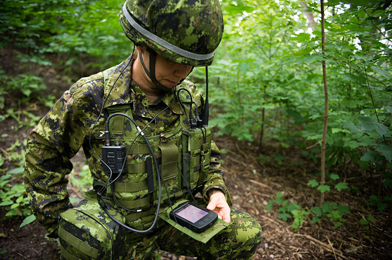 Une militaire des Forces armées canadiennes fait la démonstration d'un ensemble de matériel militaire pour le Projet d'équipement intégré du soldat.