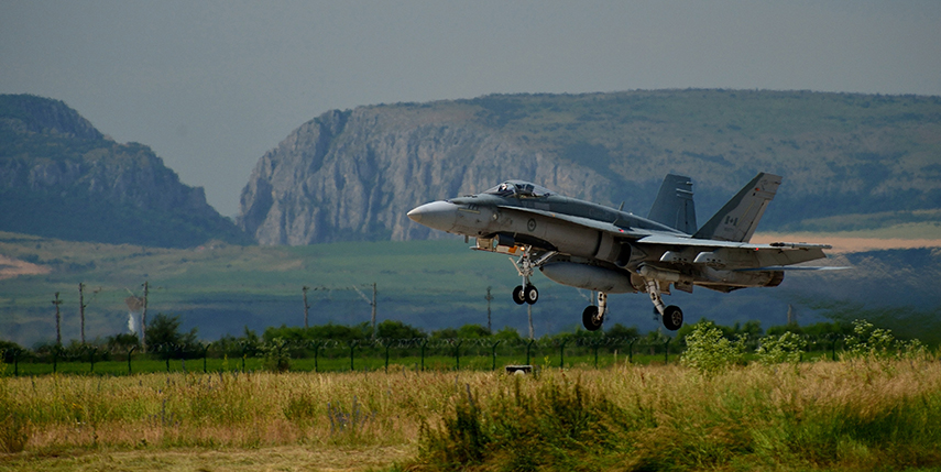 Un chasseur CF-18 Hornet canadien décolle en vue de participer à des opérations d’entraînement, le Cheile Turzii en arrière-plan, le 19 juin 2014, à Câmpia Turzii, en Roumanie, au cours de l’opération REASSURANCE.