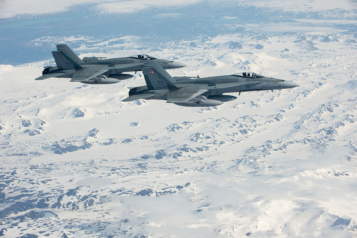 Deux CF-18 Hornet du 425e Escadron d’appui tactique de Bagotville (Québec) survolent les montagnes islandaises, le 1er mai 2014, après avoir quitté Keflavik (Islande), où ils ont appuyé les mesures d’apaisement de l’OTAN. Photo : Caporal-chef Roy MacLellan, Imagerie de la 8e Escadre TN2014-0142-028