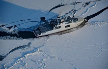 Un rendu du navire de la classe Harry DeWolf : vue aérienne, côté tribord arrière en mer glacée.