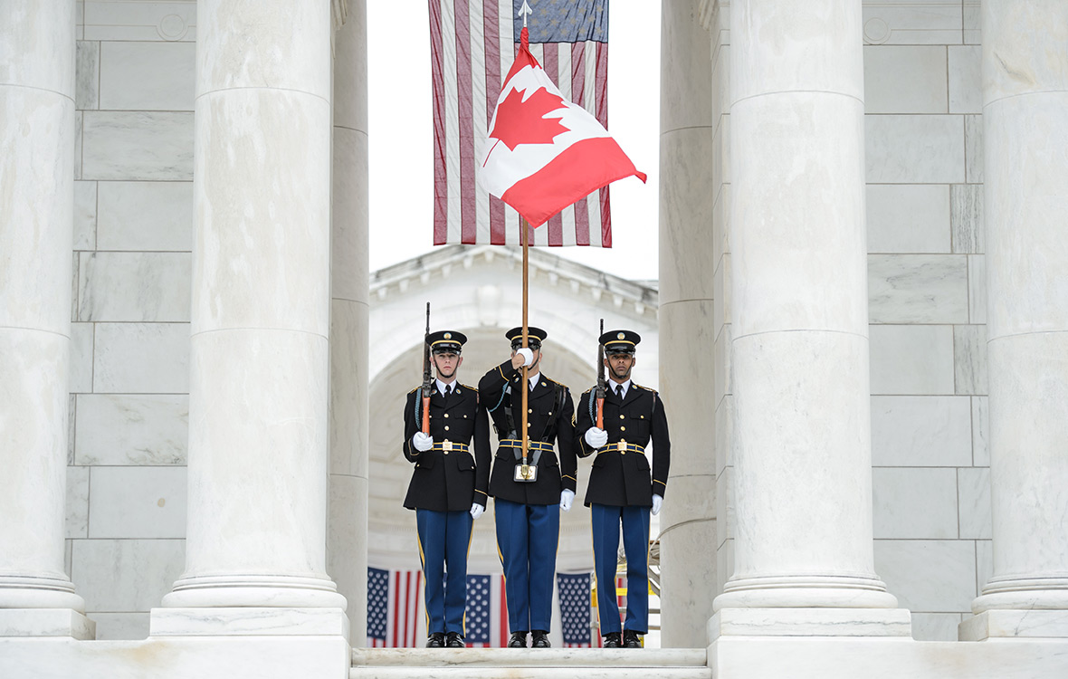Des soldats américains se tiennent au garde-à-vous avec le drapeau canadien lors d'une cérémonie de dépôt de couronnes au cimetière d'Arlington, en Virginie, le 23 mai 2017.  Crédit photo: Caporal Chase Miller Services d'imagerie de l'Unité de soutien des Forces canadiennes (Ottawa)