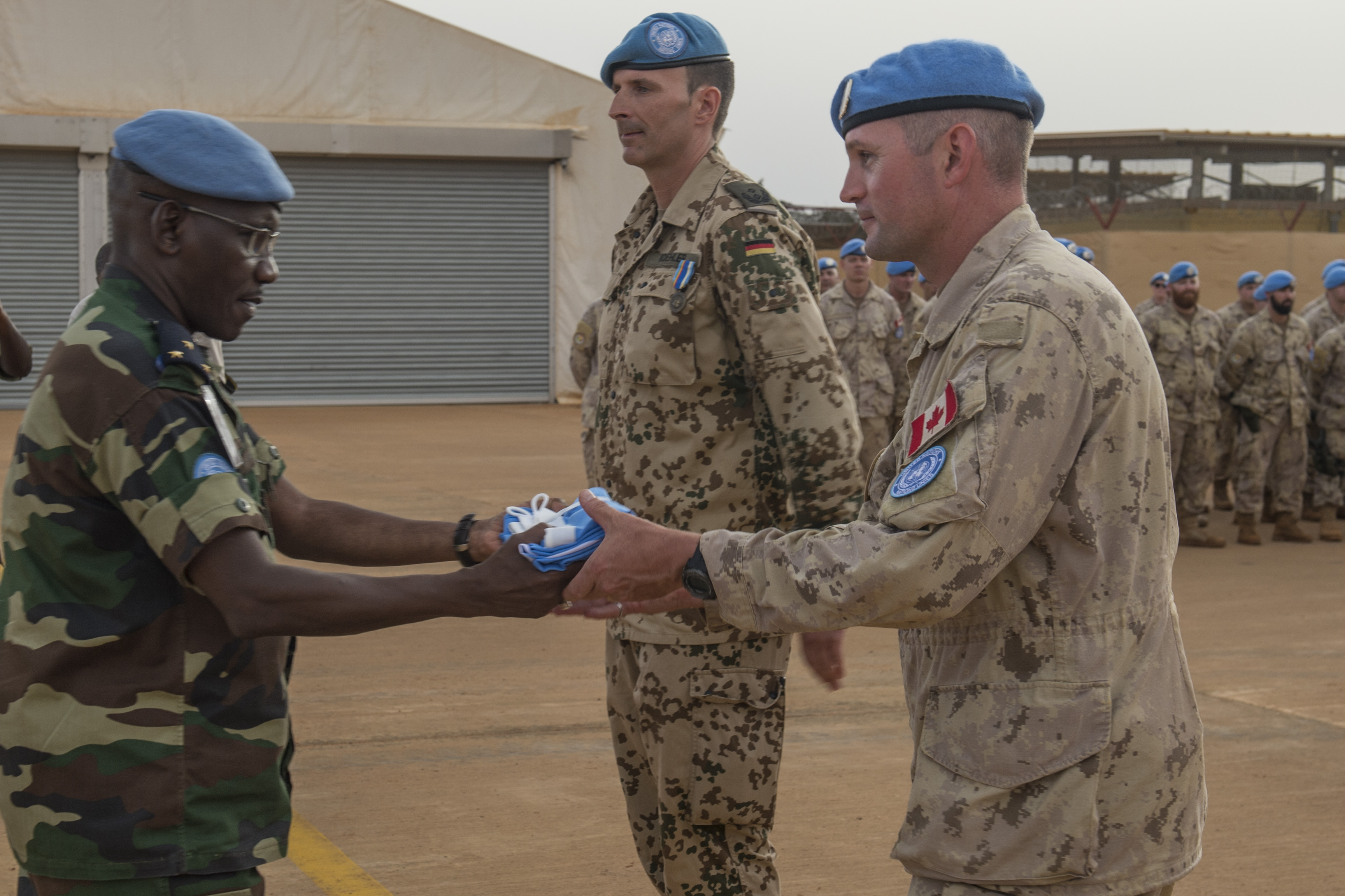 A soldier passes a United Nations flag to another soldier