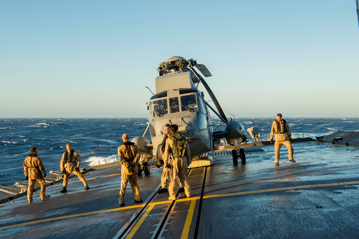 Des membres d’équipage du détachement aérien du Navire canadien de Sa Majesté Charlottetown s’apprêtent à ranger l’hélicoptère CH-124 Sea King dans le hangar au cours de l’opération REASSURANCE, le 6 octobre 2017. Photo : Caporal J.W.S. Houck, Services d’imagerie de la formation RP11-2017-0822-2454