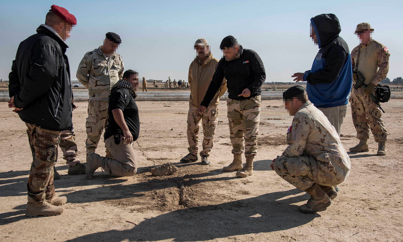 L’image a été modifiée numériquement pour des raisons de sécurité opérationnelle. Un militaire du Corps du génie royal canadien de l’équipe d’instruction sur les dangers des explosifs (troisième à partir de la droite) observe un soldat irakien (quatrième à partir de la droite) qui enseigne à d’autres soldats irakiens comment réagir en présence d’un dispositif explosif de circonstance (IED), au cours de l’opération IMPACT, le 28 novembre 2017. Photo : Op Impact, MDN.