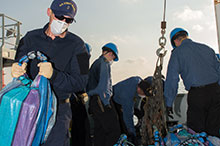 Des marins canadiens et des membres du détachement d’application de la loi de la Garde côtière américaine font le tri des sacs qui ont été récupérés après avoir été jetés par dessus bord depuis un navire d’intérêt au cours de l’opération CARIBBE, le 25 mars 2016. (Photo : OP Caribbe, MDN)