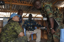 Kinshasa, Democratic Republic of Congo. 9 June 2007 – Major Louis Xenos (left) and Lieutenant Commander Yusuf Ibrahim from Nigeria, discuss concerns for medical supplies in a community hospital with local villagers from an island community on the Congo River near the city of Kinshasa, Democratic Republic of Congo while on a fact-finding mission to gather information from the local population during Operation CROCODILE. (Photo by MCpl Robert Bottrill, Canadian Forces Combat Camera)