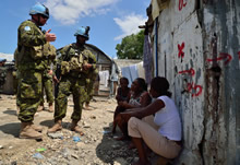Port-au-Prince (Haïti), 3 septembre 2013 – Le sergent Pierre-Alexandre Ruegsegger (à gauche) et le soldat Gelin (à droite), tous deux du 2e Bataillon, Royal 22e Régiment, discutent avec des résidents du camp Jean-Marie Vincent dans le cadre de l’opération Hamlet. (Photo: Cplc Marc-André Gaudreault, Caméra de combat des Forces canadiennes)