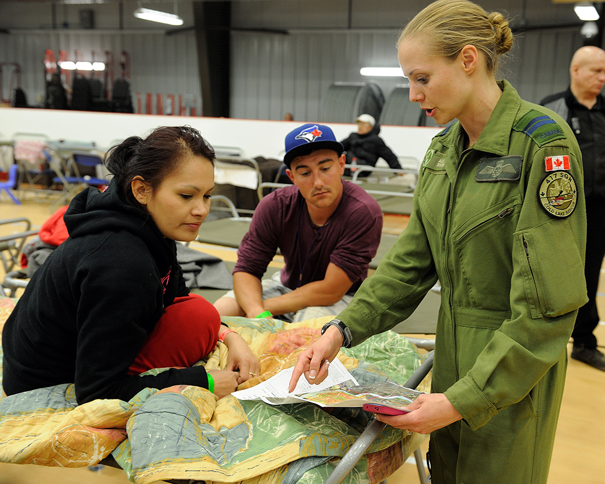 La capitaine Alexia Shore du 417e Escadron de soutien au combat s’adresse à des résidents évacués de la région de Fort McMurray, au centre de loisirs d’Anzac, en Alberta, le 4 mai 2016. Les Forces armées canadiennes ont déployé des ressources aériennes dans la région afin d’aider la province de l’Alberta dans le cadre des opérations d’intervention d’urgence. Photo : Cplc VanPutten, Services d’imagerie 3 BSDC 