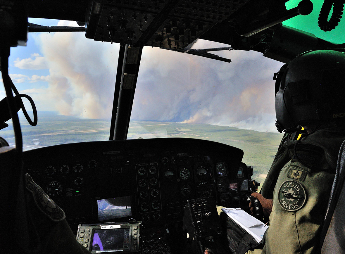 Des membres du 408e Escadron d’hélicoptères tactiques basé à Edmonton constatent les dégâts causés par les feux de forêt dans la région de Fort McMurray, à bord d’un hélicoptère CH-146 Griffon, le 5 mai 2016. Les Forces armées canadiennes déploient des ressources aériennes à l’appui des mesures d’urgence prises par la province de l’Alberta en vue de combattre les feux de forêt. Photo : Cplc VanPutten,  Services d’imagerie, BS 3 Div C