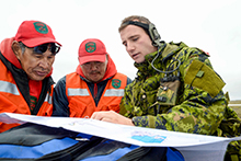 Le capitaine Matthew Szostk (à droite), membre du Royal Montreal Regiment, discute des itinéraires possibles avec le caporal chef Andy Aliyak (à gauche) et le ranger John Ussak (au centre), membres du 1er Groupe de patrouilles des Rangers canadiens, près de Rankin Inlet, au Nunavut, au cours de l’opération NANOOK, le 21 août 2016. (Photo : Maître de 2e classe Belinda Groves, technicienne en imagerie de la Force opérationnelle)