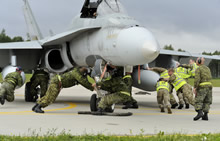 Des spécialistes de la maintenance de la Royal Air Force et de l’Aviation royale canadienne déplacent un CF188 Hornet, à la base aérienne de Šiauliai (Lituanie), en vue d’appuyer les opérations du bloc 36 de la police aérienne des pays baltes de l’OTAN, le 27 août 2014, dans le cadre de l’opération Reassurance. Photo : Cpl Kenneth Galbraith, CIIFC/Caméra de combat RE2014-0048-014