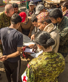 Des membres de l’équipe des éléments de base de l’Équipe d'intervention en cas de catastrophe (EICC) discutent avec des représentants locaux durant une patrouille de reconnaissance dans le cadre de l’aide apportée aux victimes du séisme au Népal par le gouvernement du Canada, le 2 mai 2015 Photo: Sgt Yannick Bédard, Caméra de combat des Forces canadiennes.