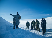 Resolute Bay, Nunavut. 4 April 2016. American Staff Sergeant Matt Hinds of the Northern Warfare Training Center instructs members of the 2nd Battalion, The Royal Canadian Regiment on the construction of a snow cave near Resolute Bay, NU, in preparation for Operation NUNALIVUT April 4, 2016. (Photo: Cpl Parks, Task Force Image Technician)