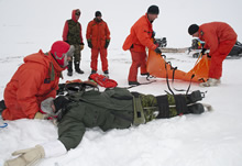 Baring Bay (Nunavut), 22 avril 2012 – Le sergent (Sgt) Eric Soubrier, technicien en recherche et sauvetage (SAR), immobilise le cou de la fausse victime alors que le Sgt Stephane Clavette et le caporal-chef Sean Daniell, techniciens SAR, préparent la civière SKED au lieu de l’accident avant de transporter la victime vers un endroit plus chaud lors d’un exercice SAR, à Baring Bay (Nunavut), dans le cadre de l’opération Nunalivut 2012.
