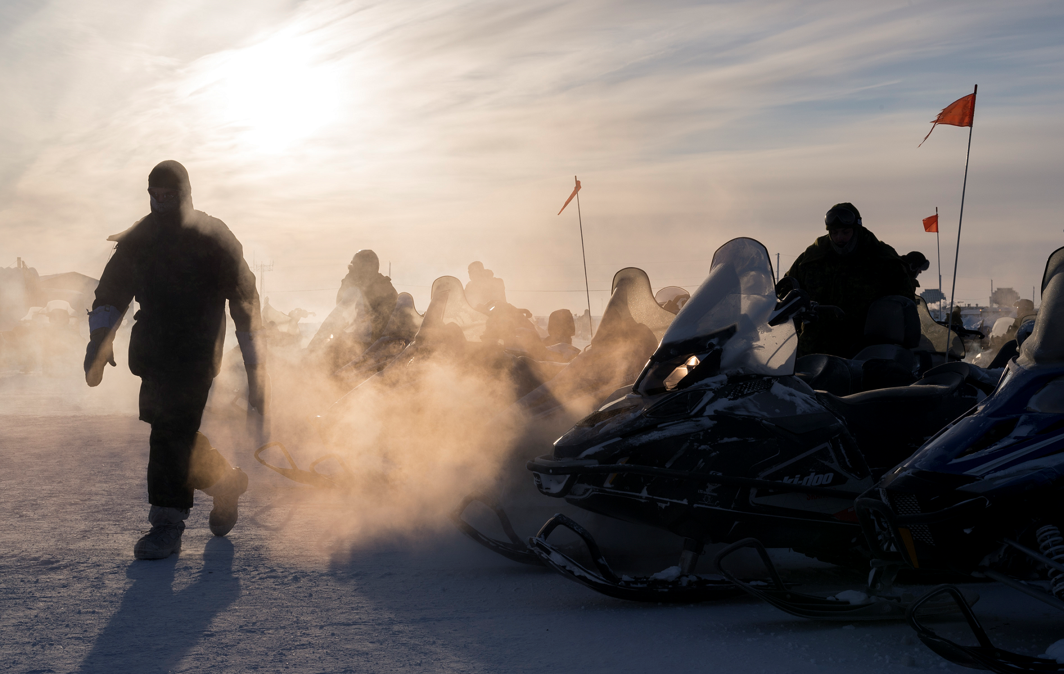 24 février 2017. Des membres en déploiement du 12e Régiment blindé du Canada réchauffent les moteurs des motoneiges en vue d’une patrouille au cours de l’opération NUNALIVUT 2017, à Hall Beach, au Nunavut, le 24 février 2017. (Photo : Sgt Jean-François Lauzé, technicien en imagerie de la Force opérationnelle)
