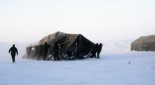 Des militaires en mission du 12e Régiment blindé du Canada fixent en place une tente modulaire par vent fort pendant l’opération NUNALIVUT 2017 à Hall Beach (Nunavut), le 22 février 2017. (Photo : M 2 Belinda Groves, technicienne en imagerie de la force opérationnelle)