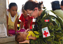Lieutenant (Navy) Melanie Espina, doctor for the 1st Canadian Field Hospital, Petawawa, and member of the Canadian Armed Forces Disaster Assistance Response Team, examines a local baby during Operation RENAISSANCE, in Sara, Philippines on November 21, 2013. Photo: MCpl Marc-Andre Gaudreault, Canadian Forces Combat Camera IS2013-2006-058