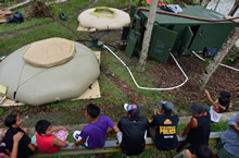 Locals observe a Canadian Armed Forces Reverse Osmosis Water Purification Unit used during Operation RENAISSANCE, in Dumarao, Philippines on November 23, 2013. Photo: MCpl Marc-Andre Gaudreault, Canadian Forces Combat Camera IS2013-2006-074