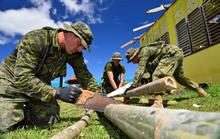 Gunner Shane Bristow (front) from 2 Royal Canadian Horse Artillery (2 RCHA), Petawawa, Corporal Joel Majaralie (middle) from 2 Combat Engineer Regiment, Petawawa and Gunner Nicholas Hearty from 2 RCHA, Petawawa cuts bamboo poles to build an evacuation shelter to let kids recover their classrooms that is currently used by typhoon Haiyan evacuees during Operation RENAISSANCE, in Pontevedra, Philippines on November 24, 2013. Photo: MCpl Marc-Andre Gaudreault, Canadian Forces Combat Camera IS2013-2006-091