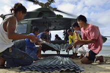 Local citizens help Royal Canadian Air Force personnel to unload construction materials for building homes, from a CH-146 Griffon helicopter during Operation RENAISSANCE, on Olotayan Island, Philippines on November 30, 2013. Photo: MCpl Marc-Andre Gaudreault, Canadian Forces Combat Camera IS2013-2006-155