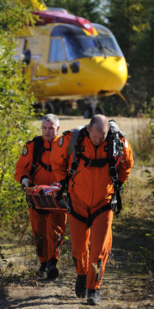 Le caporal-chef (Cplc) Rob Featherstone et le Cplc Jeff Connors, techniciens en recherche et sauvetage, transportent une civière depuis un hélicoptère CH149 Cormorant jusqu’à un site d’écrasement simulé d’un avion Cesna, le 9 octobre 2013, dans le cadre d’un exercice de recherche et sauvetage mené à Miramachi (Nouveau-Brunswick). (Photo : Cpl Crystal Roche, Imagerie de la 14e Escadre Greenwood)