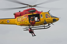 Lac Simcoe (Ontario). Le 5 mai 2015 - Un mécanicien de bord fait descendre un technicien en recherche et sauvetage du 424e ETS de la 8e Escadre Trenton au sol à partir d’un hélicoptère Griffon au cours de l’exercice TIGER 2015 se déroulant à l’aéroport du lac Simcoe. (Photo : Caporal-chef Lori Geneau, Service d’imagerie de la 8e Escadre)