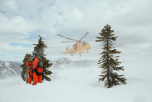 Hope (Colombie-Britannique). Le 27 février 2014 -  Des techniciens en recherche et sauvetage du 442e Escadron de transport et de sauvetage discutent de leur plan d’action, au sol, tandis qu’un hélicoptère Cormorant s’approche en vue d’atterrir au sommet d’une montagne, près de Hope (Colombie-Britannique), le 27 février 2014, dans le cadre d’un exercice annuel de recherche et sauvetage. (Photo : Bdr Albert Law, 39e Groupe-brigade du Canada)