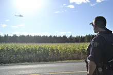 Ontario. 16 Septembre 2013 – Un membre de la Gendarmerie royale du Canada et un hélicoptère CH146 Griffon scrutent une plantation de marijuana dans l’est de l’Ontario, dans le cadre de l’opération Sabot. (Photo par Caméra de combat des Forces canadiennes)