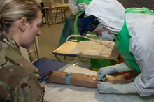 Strensall, Royaume-Uni. Le 11 décembre 2014 – Un membre de l’équipe médicale des Forces armées canadiennes prélève un échantillon de sang sous la supervision d’un employé de l’équipe du Royaume-Uni, au cours de l’entraînement préalable au déploiement en vue de l’opération SIRONA avec leurs homologues britanniques, au Centre d’instruction des services médicaux de l’armée, à Strensall, au Royaume-Uni. (Photo : Sgt Yannick Bedard, Caméra de combat des Forces canadiennes)