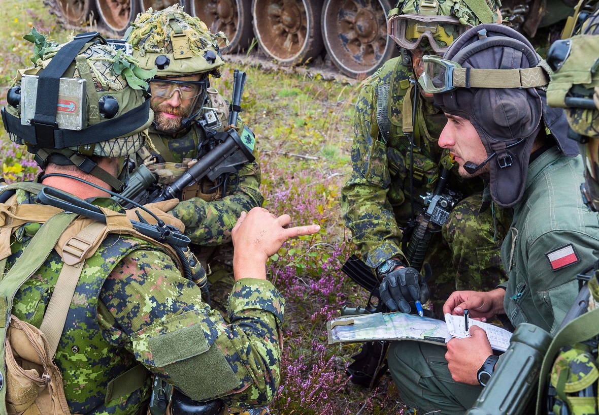 Canadian soldiers with NATO's enhanced Forward Presence Battlegroup Latvia coordinate a plan with a Polish tank commander on August 24, 2017, during the Certification Exercise being held at Camp Adazi, Latvia. Photo: Cpl Jordan Lobb, Canadian Forces Combat Camera IS14-2017-0003-095