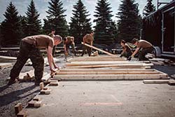 Des soldats de la Force opérationnelle interarmées (Est) construisent des planchers de bois qui seront installés dans les tentes érigées pour abriter les demandeurs d’asile près du poste frontalier de Saint-Bernard-de-Lacolle, au Québec, au cours de l’opération ELEMENT, le 11 août 2017. Photo : Caporal Djalma Vuong-De Ramos, BAP 2 DIV C / FOI (Est)