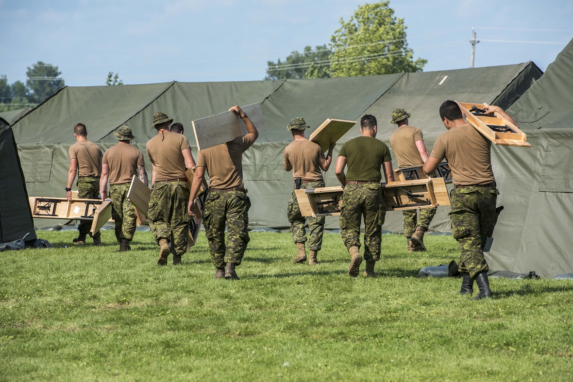 Les Royal Canadian Dragoons transportent des tables pour les installer dans la ville de tentes construite au centre de NAV CANADA à Cornwall, en Ontario, durant l’opération ELEMENT, le 18 août 2017. Photo par le Cpl Veldman, Imagerie de la Garnison Petawawa