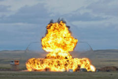 A large burst of flames and shock wave engulfs a series of concrete structures built for an explosives trial on the Experimental Proving Ground at DRDC – Suffield Research Centre.