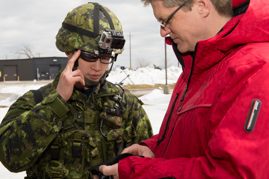 A defence scientist prepares a smartphone for the trial with a Canadian Armed Forces soldier wearing a Google Glass heads up display. 