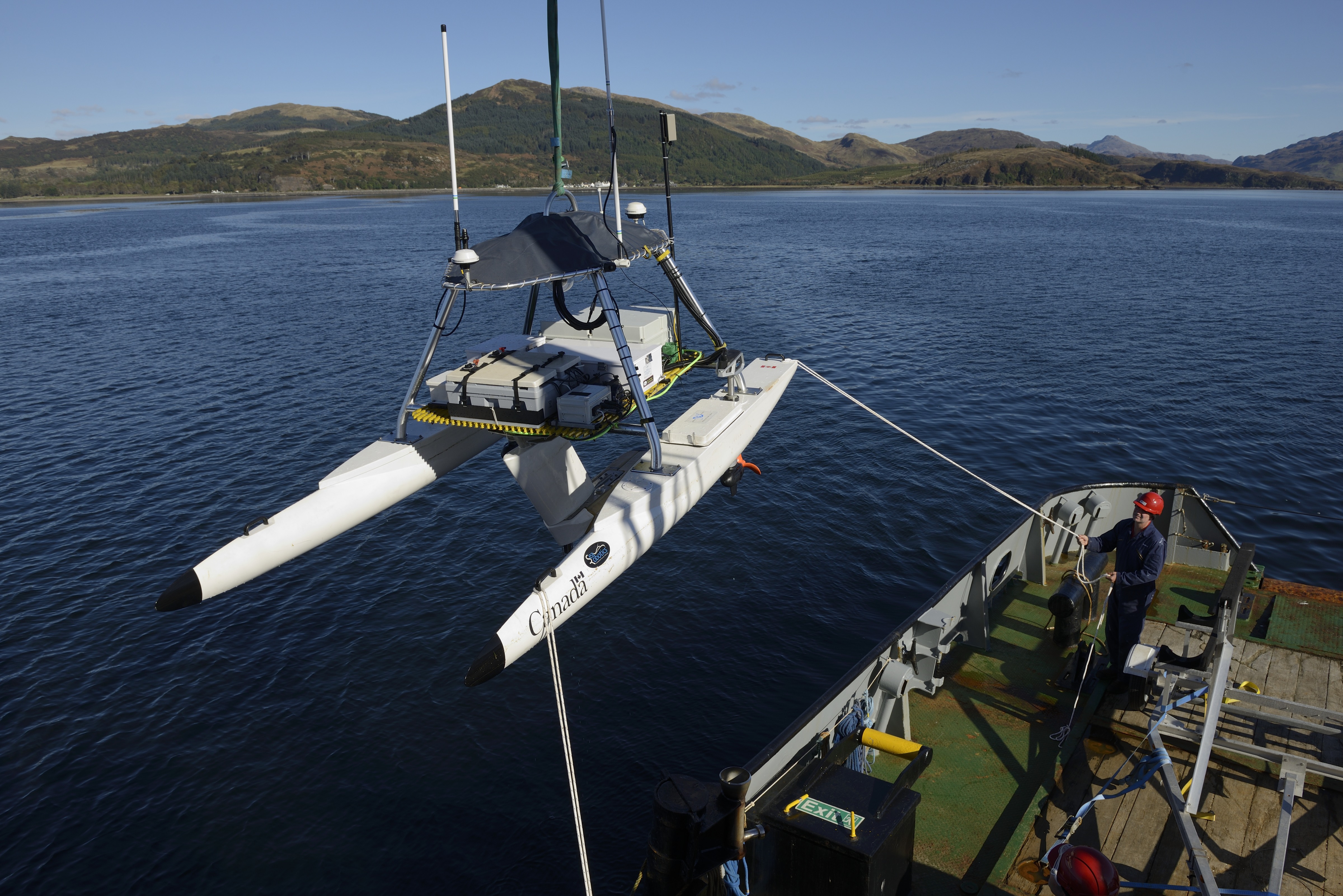 The ship’s crew uses a crane to launch Defence Research and Development Canada’s unmanned surface vehicle USV-2600 into the water at Loch Alsh. Photo by Janice Lang, DRDC