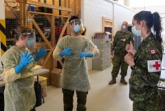 Des membres des Forces armées canadiennes revêtent l’équipement de protection individuel (EPI) alors qu’ils s’acquittent de leurs fonctions opérationnelles dans des établissements de soins de longue durée dans le cadre de l’opération LASER.