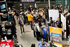A crowd of students walk by signs