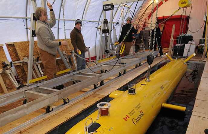 An Autonomous Underwater Vehicle (AUV) is raised out of the Arctic ice using a gantry system.