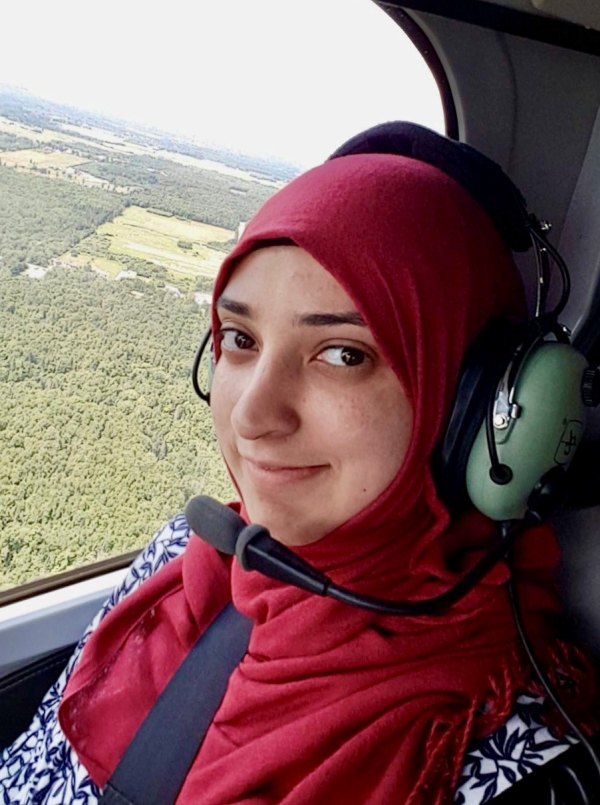 Shizrah is in a helicopter flying over a forest.