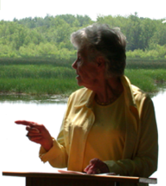 Mrs. Marcelle Cordeau-Parent speaking in front of a lake