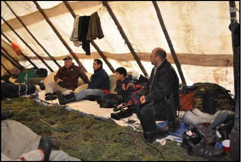 Des aînés discutant à l'intérieur d'une tente. 