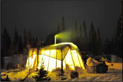 Une tente innue illuminée tard le soir.