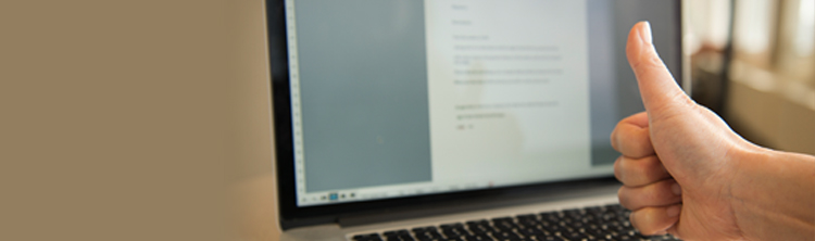 A hand is doing a thumb’s up in front of open laptop