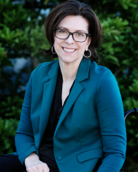 Stephanie Cadieux, seated in her wheelchair, wearing a teal blazer.