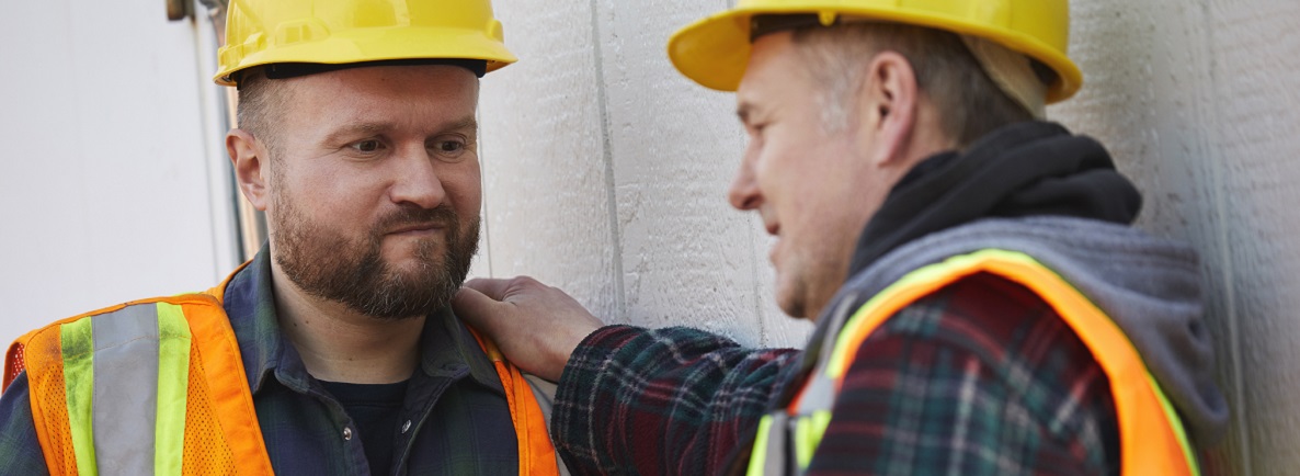 Two men in a serious but supportive conversation at a construction job site