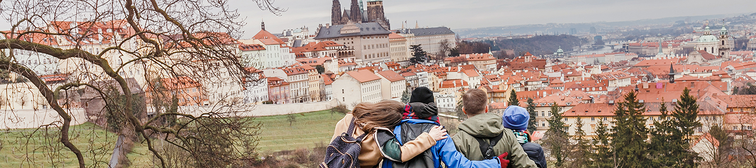 Four friends hug as they look over a city in the Czech Republic