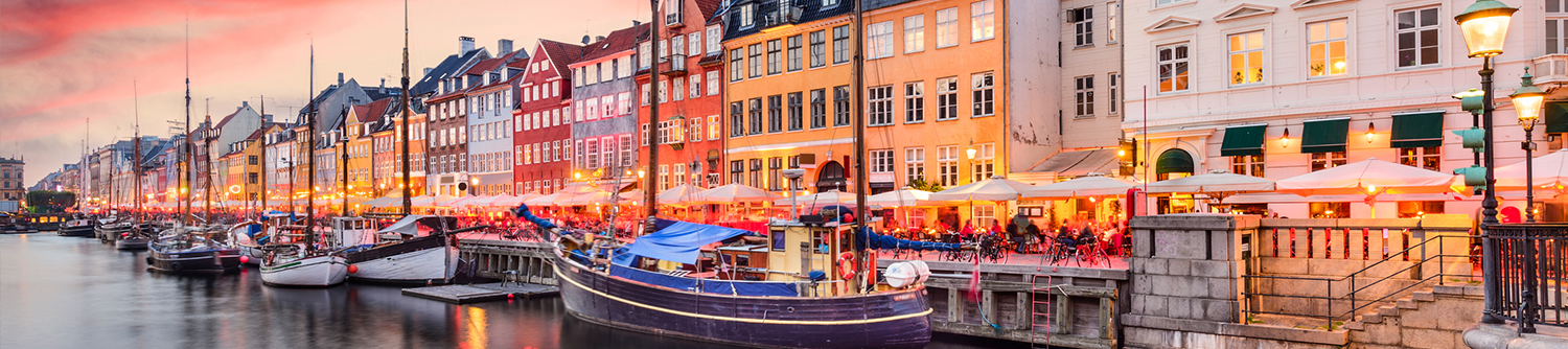 A busy street in Denmark lined with colourful buildings in front of a canal.