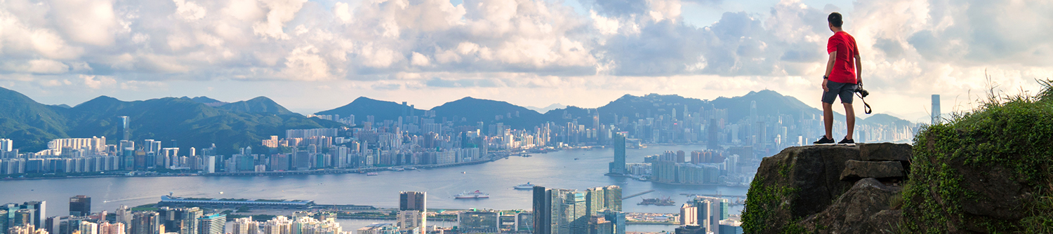 Une personne est perchée sur une falaise et observe le panorama de Hong Kong.