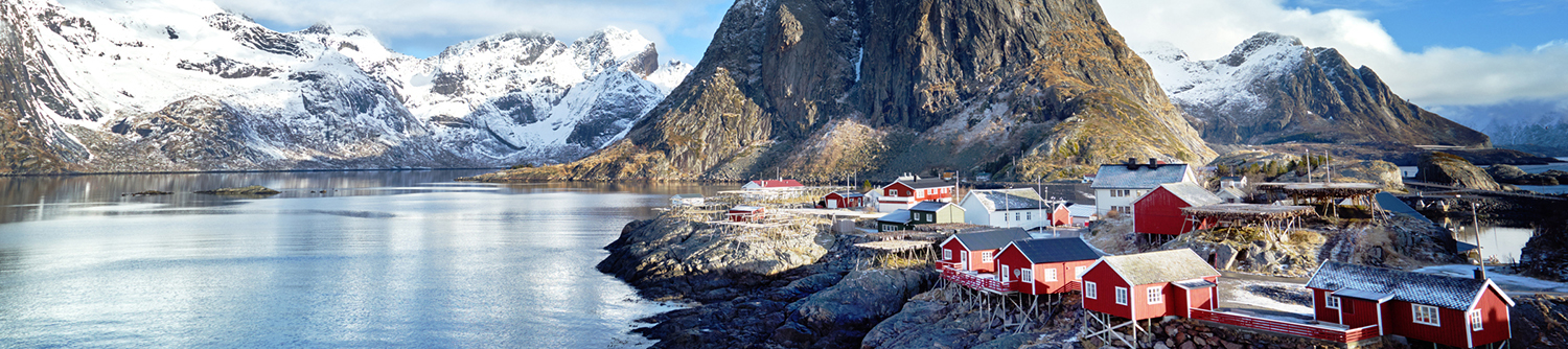 Des montagnes enneigées se trouvent derrière une ville près de l’eau en Norvège
